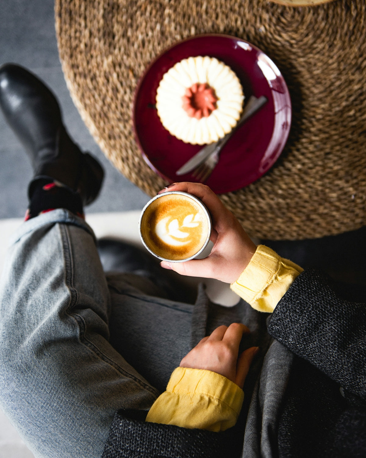 Person holding latte art coffee next to dessert