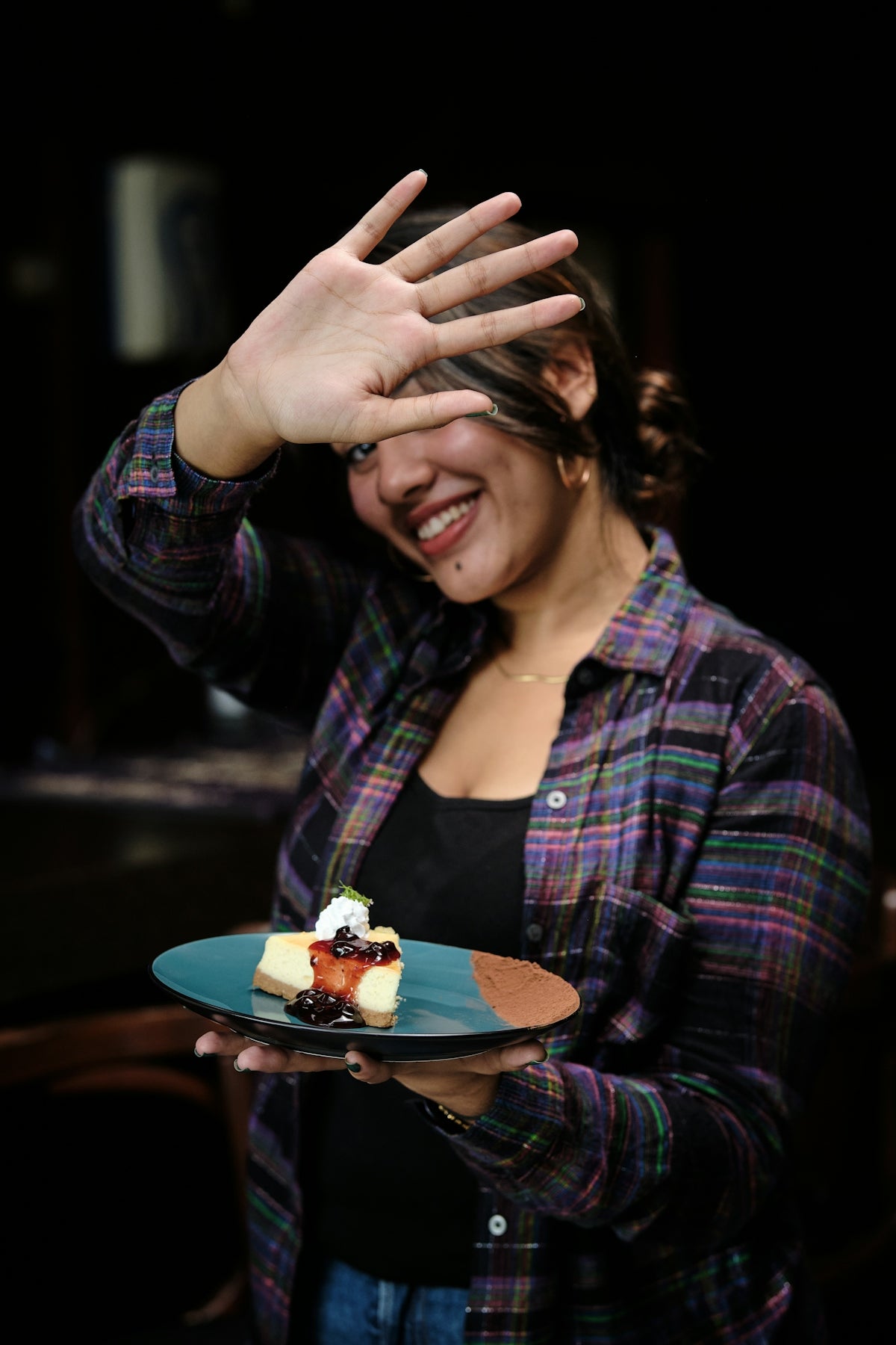 a woman holding a plate with a piece of cake on it