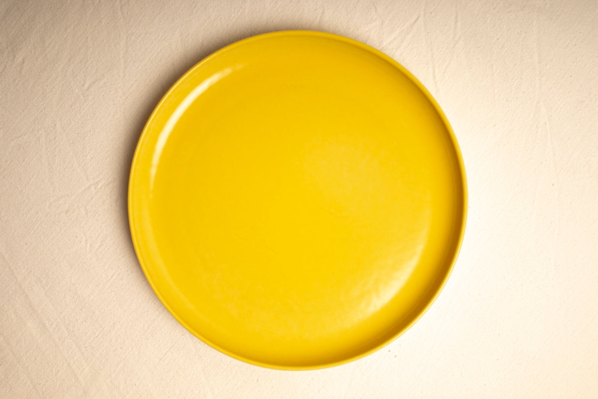 A yellow plate sitting on top of a white table