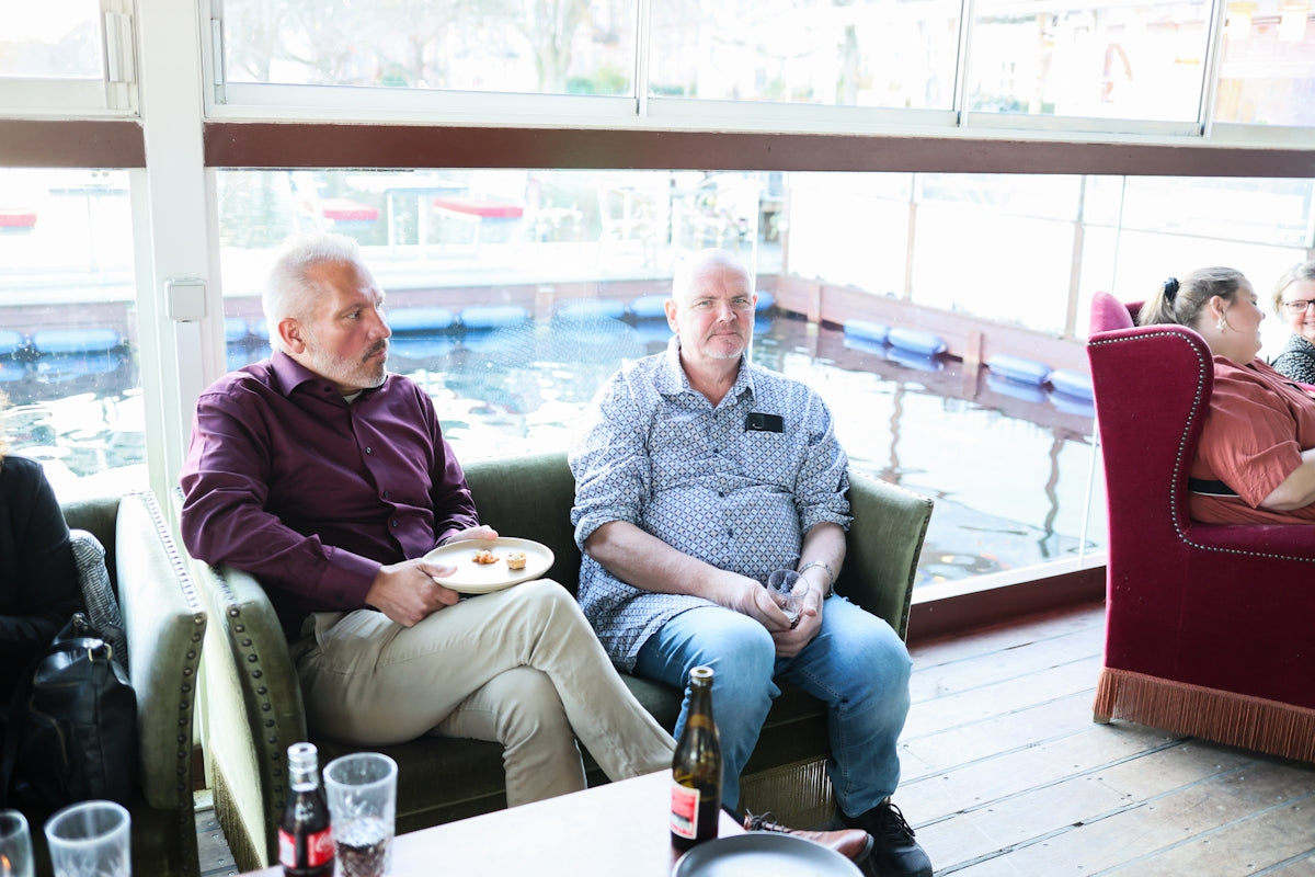 Two men sitting in armchairs by a pool.