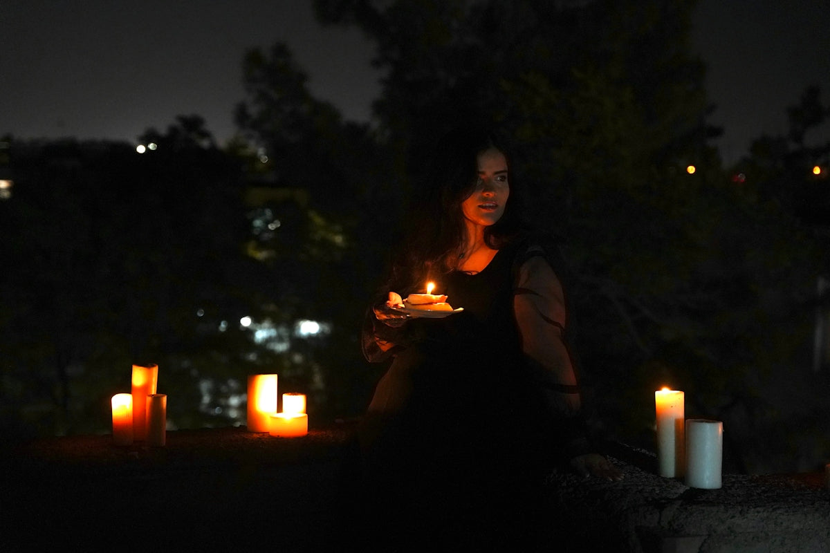 Woman holding cake, surrounded by glowing candles at night